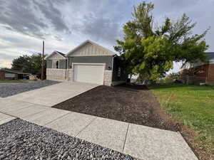 View of front of home featuring board and batten siding, an attached garage, concrete driveway, and a front yard