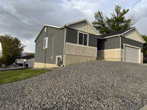 View of side of property featuring an attached garage, stone siding, board and batten siding, and stucco siding