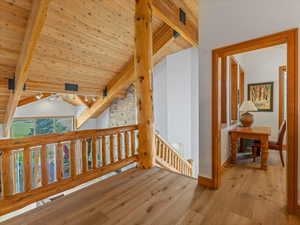 Corridor featuring wood finished floors, wooden ceiling, and an upstairs landing