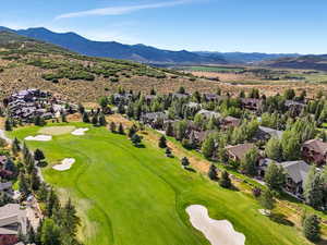 Aerial view of residential area featuring a mountainous background and a golf course