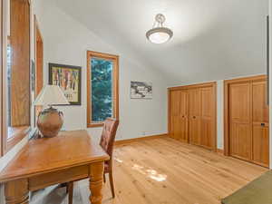 Office space featuring vaulted ceiling and light wood finished floors