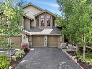 View of front facade featuring an attached garage, driveway, roof with shingles, and stucco siding