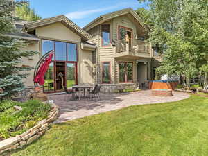 Rear view of house with a balcony, stucco siding, a patio, and a yard