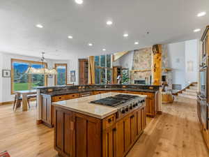 Kitchen featuring a spacious island, recessed lighting, light wood-style flooring, brown cabinets, and appliances with stainless steel finishes