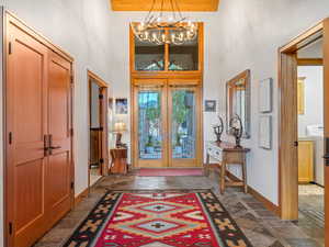 Foyer with a chandelier, french doors, stone tile floors, a towering ceiling, and washer / dryer