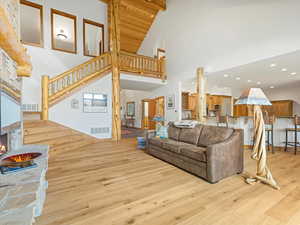 Living room featuring high vaulted ceiling, light wood-style floors, stairs, and recessed lighting