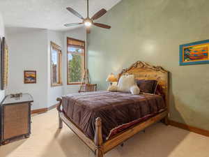 Bedroom with lofted ceiling, light carpet, and ceiling fan
