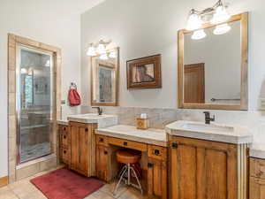 Full bathroom with tile patterned floors, a shower stall, and two vanities