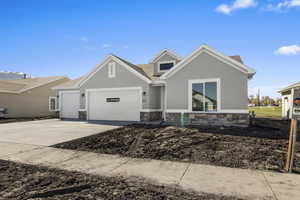 View of front of house featuring an attached garage, stone siding, concrete driveway, stucco siding, and roof with shingles