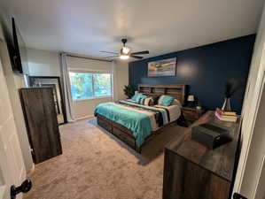Carpeted bedroom with a ceiling fan and baseboards