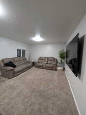 Carpeted living area with a textured ceiling and baseboards