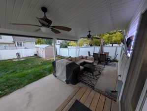 Wooden deck with a shed, a fenced backyard, outdoor dining area, and a ceiling fan