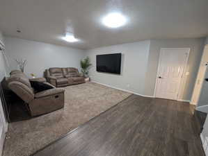 Living room with dark wood-style flooring and a textured ceiling