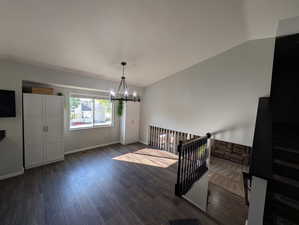 Entryway with vaulted ceiling, a chandelier, and dark wood-style flooring