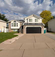 View of front facade with driveway, a garage, paid off solar panels, and brick siding