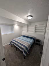 Carpeted bedroom featuring a textured ceiling and baseboards