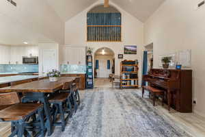 Dining area featuring high vaulted ceiling, arched walkways, and light wood finished floors