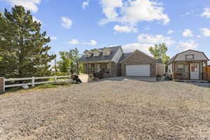 View of front of property featuring a porch, gravel driveway, a garage, and a metal roof