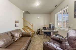 Office with carpet flooring and a textured ceiling