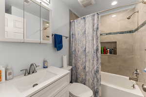 Bathroom with shower / bath combo with shower curtain, vanity, and recessed lighting