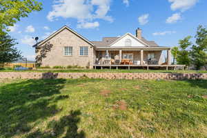 Back of property featuring a yard, a chimney, brick siding, and a wooden deck