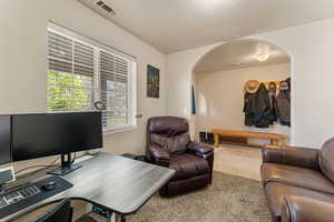 Carpeted living room featuring arched walkways, an office area, and a textured ceiling