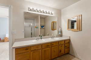 Bathroom with a stall shower, double vanity, and tile patterned flooring