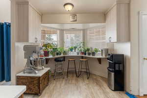 Kitchen featuring a kitchen bar, light wood-style floors, light countertops, light brown cabinetry, and a peninsula