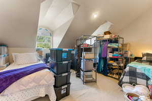 Bedroom featuring lofted ceiling and carpet flooring