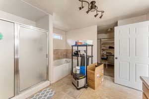 Full bath featuring a shower stall, a garden tub, and a spacious closet