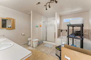 Bathroom with double vanity, a stall shower, a bath, a textured ceiling, and tile patterned flooring