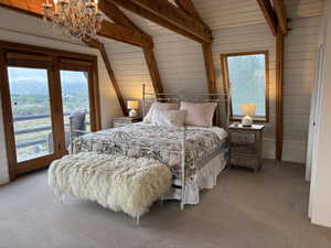 Carpeted bedroom with access to outside, wood walls, and a chandelier