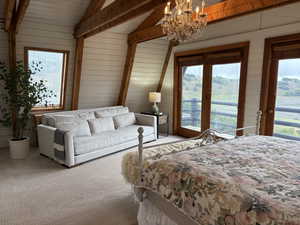 Bedroom with multiple windows, access to outside, carpet floors, a chandelier, and wood walls
