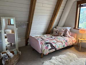 Second bedroom upstairs featuring carpet floors, wood walls with beam details and east facing window