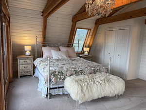 Carpeted bedroom featuring wooden walls, a closet, and a chandelier