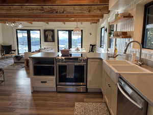 Kitchen featuring stainless stove, microwave and dishwasher, a peninsula, and white cabinetry