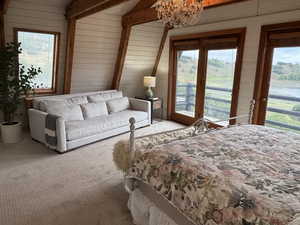 Bedroom with access to outside, wooden walls, carpet flooring, and a chandelier