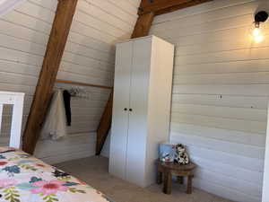 Third bedroom upstairs featuring wooden walls, exposed beam detail and wardrobe closet