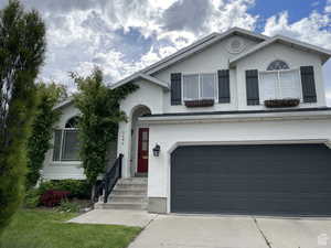 View of front facade with stucco siding, driveway, and a garage