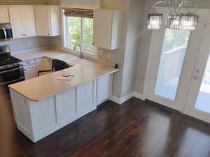 Kitchen featuring white cabinets, light countertops, stainless steel appliances, dark wood finished floors, and french doors