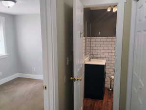 Half bath featuring vanity, tile walls, and dark wood finished floors