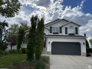 View of front of house featuring driveway, a garage, and stucco siding
