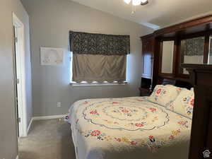 Carpeted bedroom with vaulted ceiling and baseboards