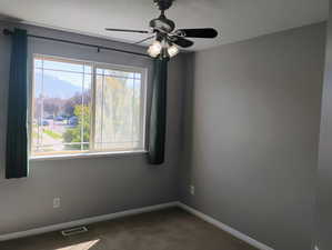 Empty room with dark carpet and ceiling fan