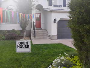 Property entrance featuring an attached garage, a lawn, and stucco siding