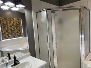 Bathroom with vanity, a shower stall, and a garden tub
