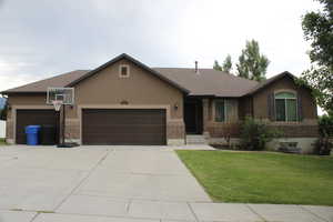 Ranch-style house with a garage, driveway, stucco siding, and a front yard