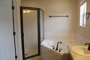 Bathroom featuring a bath, a shower stall, and vanity