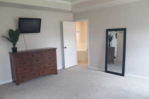 Bedroom featuring light colored carpet, connected bathroom, and ornamental molding