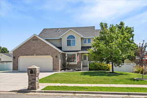 Traditional-style home with driveway, a garage, roof with shingles, and brick siding